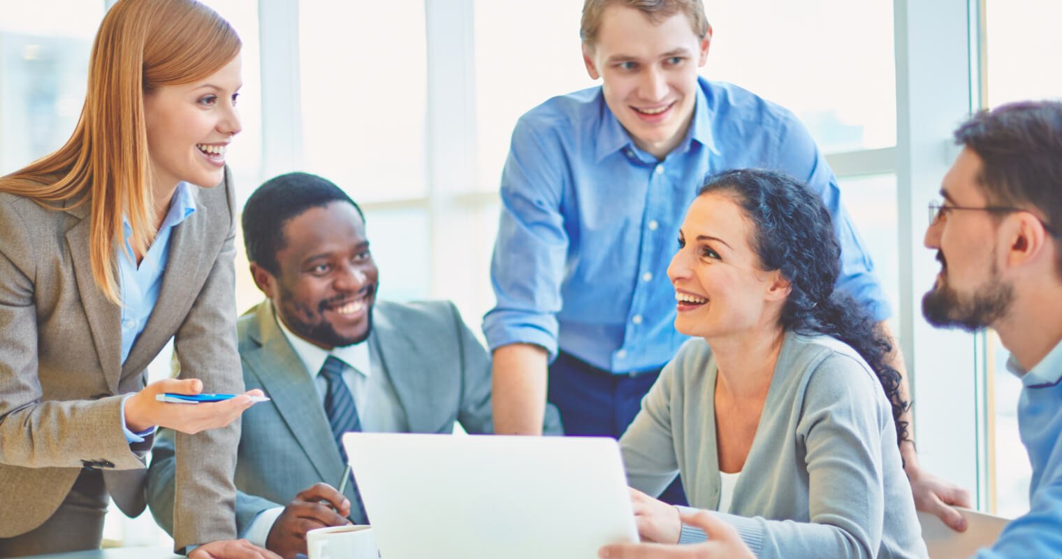 Grupa profesjonalistów w biurze siedząc przy laptopie rozmawia wykorzystując Business English